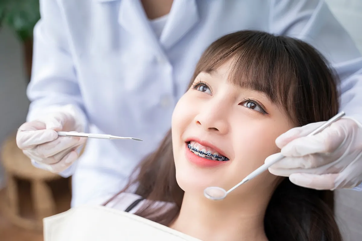 Asian woman holding her cheek with a pained expression, illustrating toothache or dental discomfort caused by sensitivity, decay or gum issues.